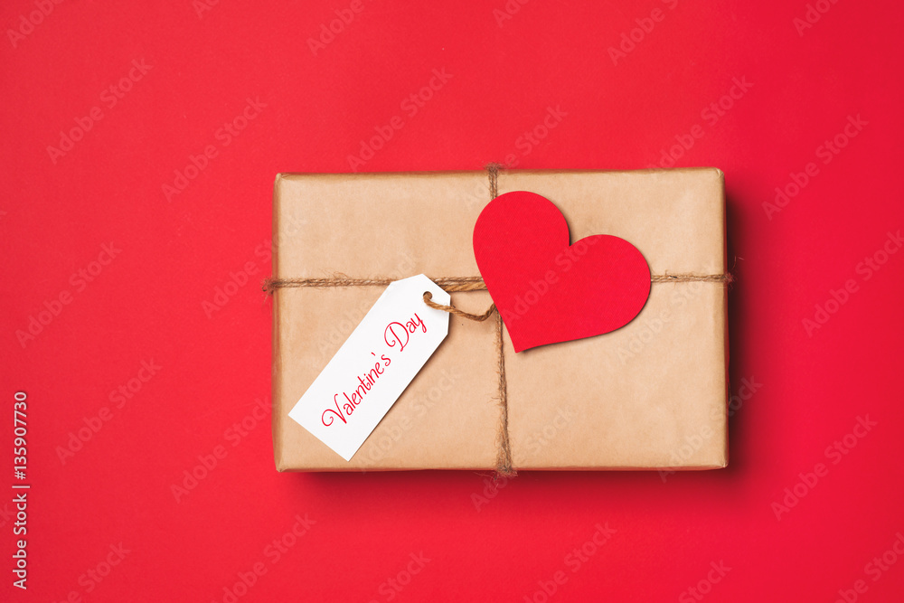 Handmade small gift box with heart symbol on red background.