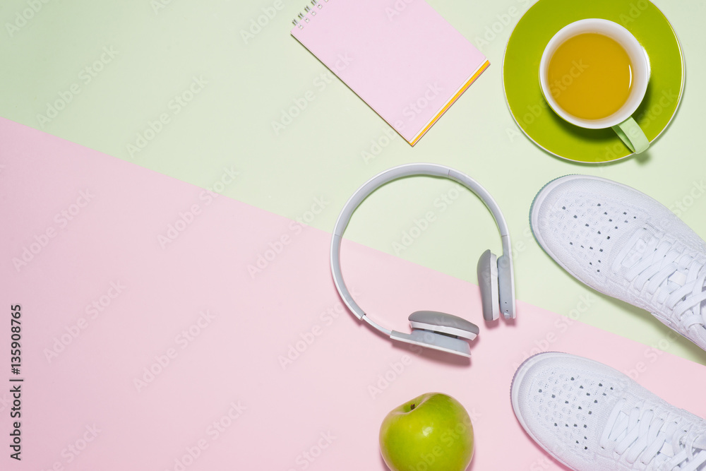 Healthy concept. Sneakers, tea, apple and headphone on pastel co