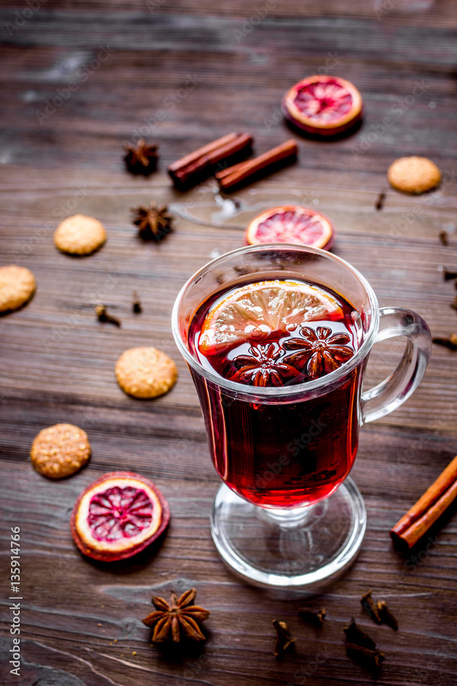 mulled wine with spices in cup on wooden background