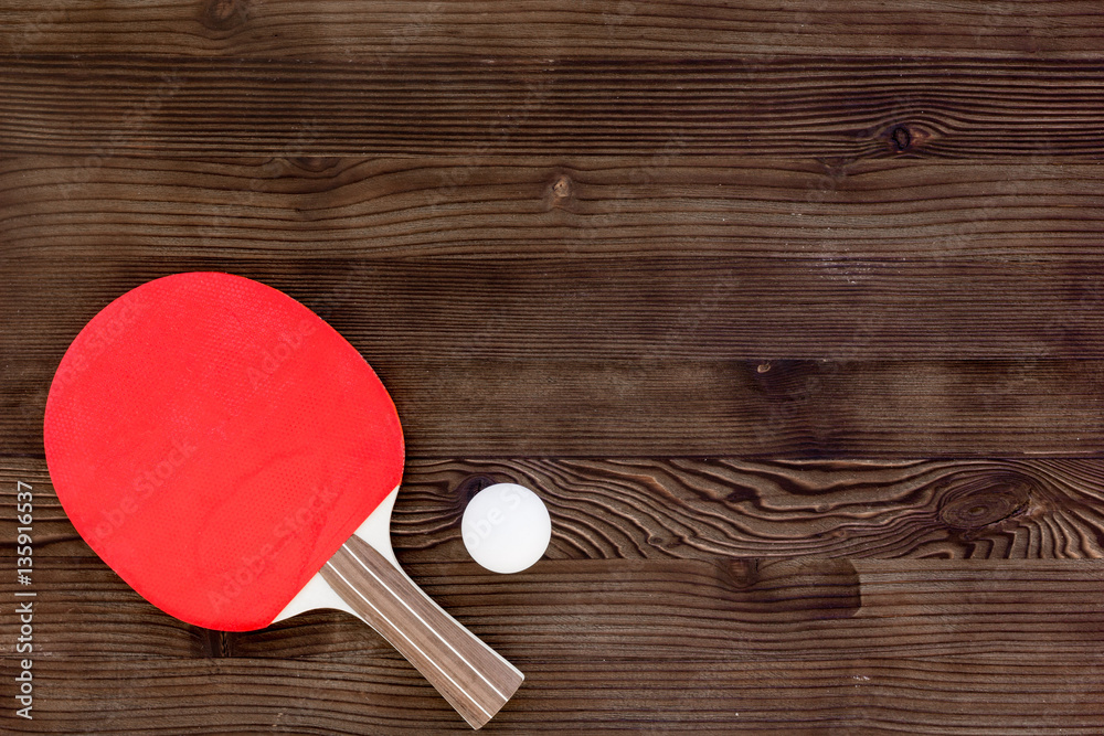 Red racket for ping pong ball wooden background top view