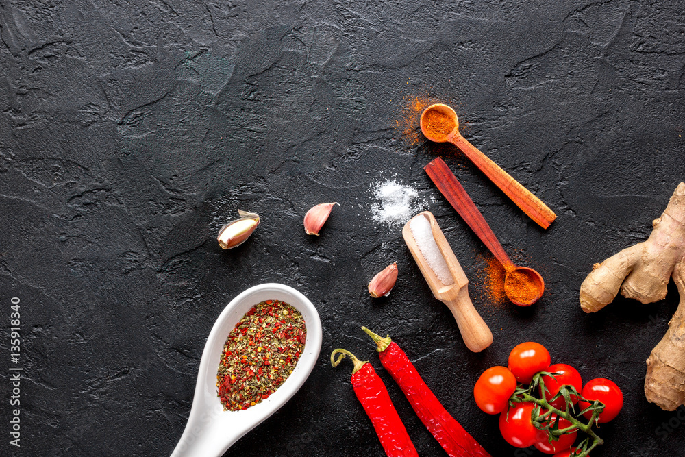 spices in wooden spoon on dark background top view