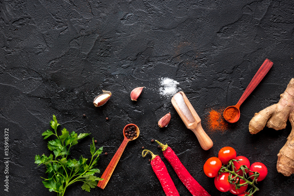 spices in wooden spoon on dark background top view