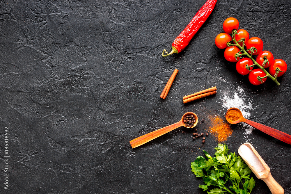 spices in wooden spoon on dark background top view