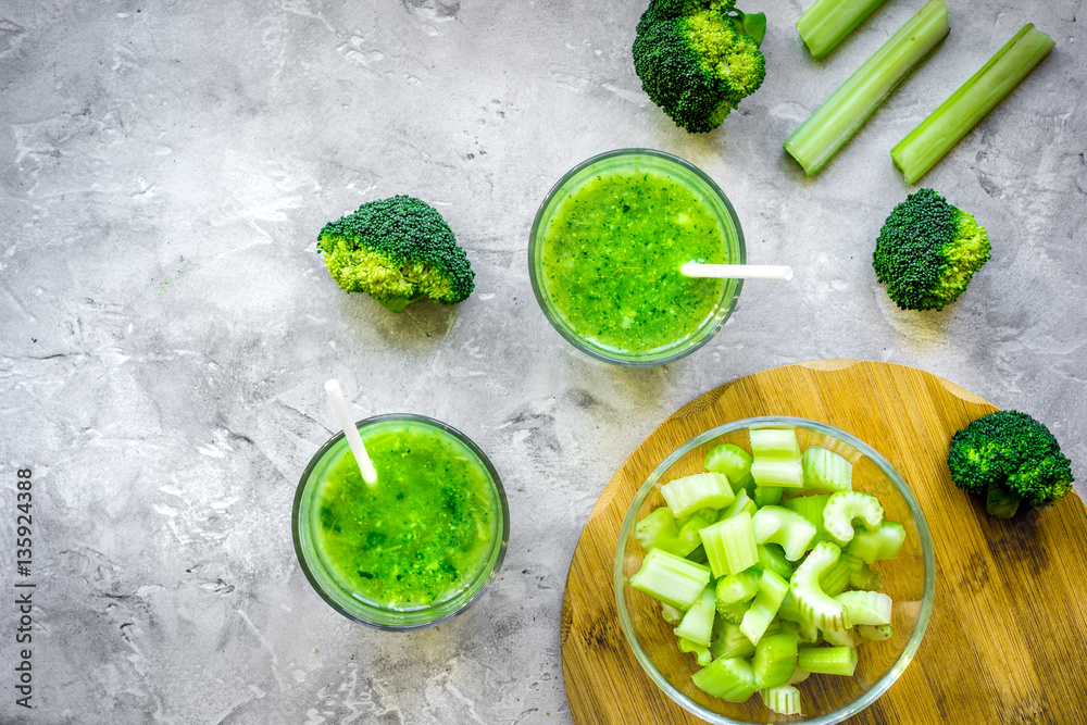 Green vegetable smoothie in glass at gray background top view