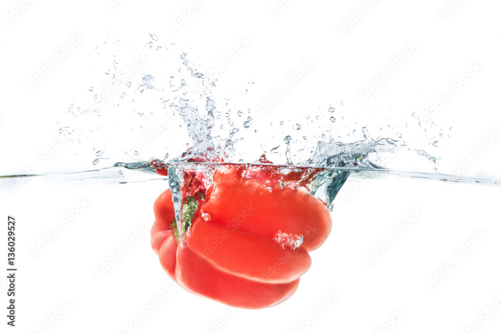 Red bellpepper dropped into the water with water splash on a whi