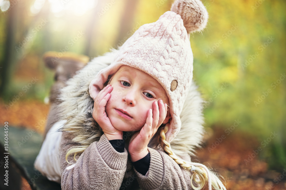 Daydreaming little girl laying on a bench