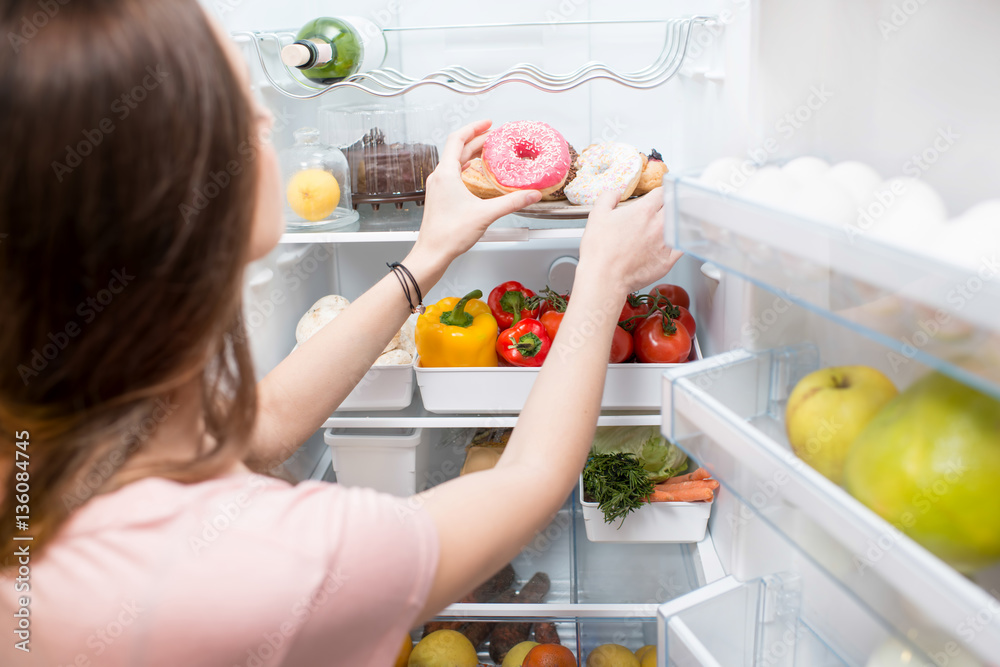 Woman taking sweet donuts from the refrigerator