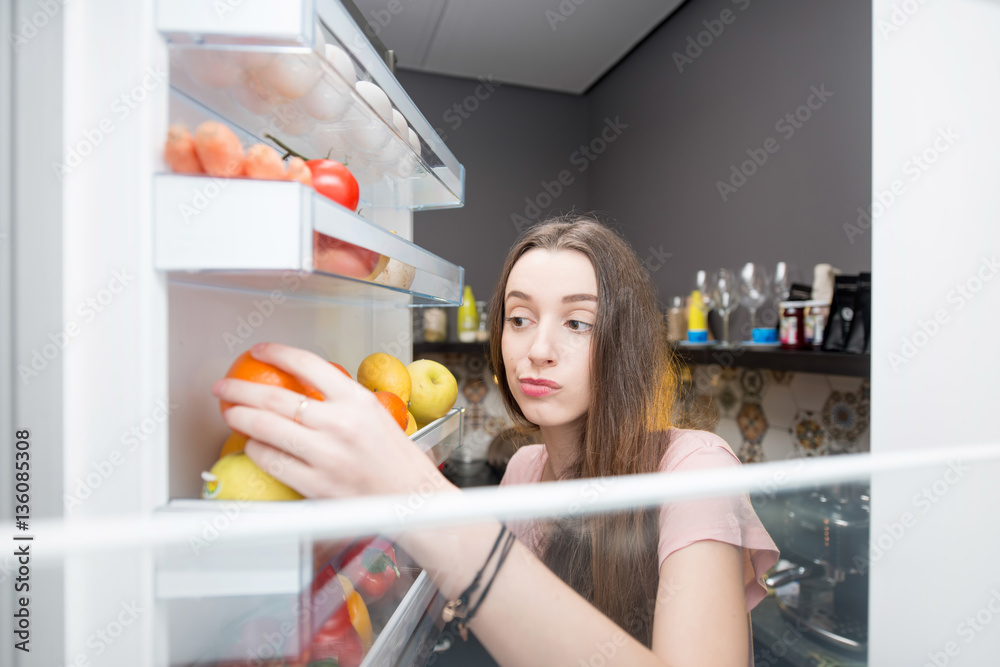 从冰箱里拿食物的女人。从里面看