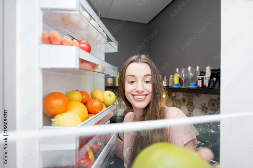 Woman taking food from the refrigerator. View from the inside