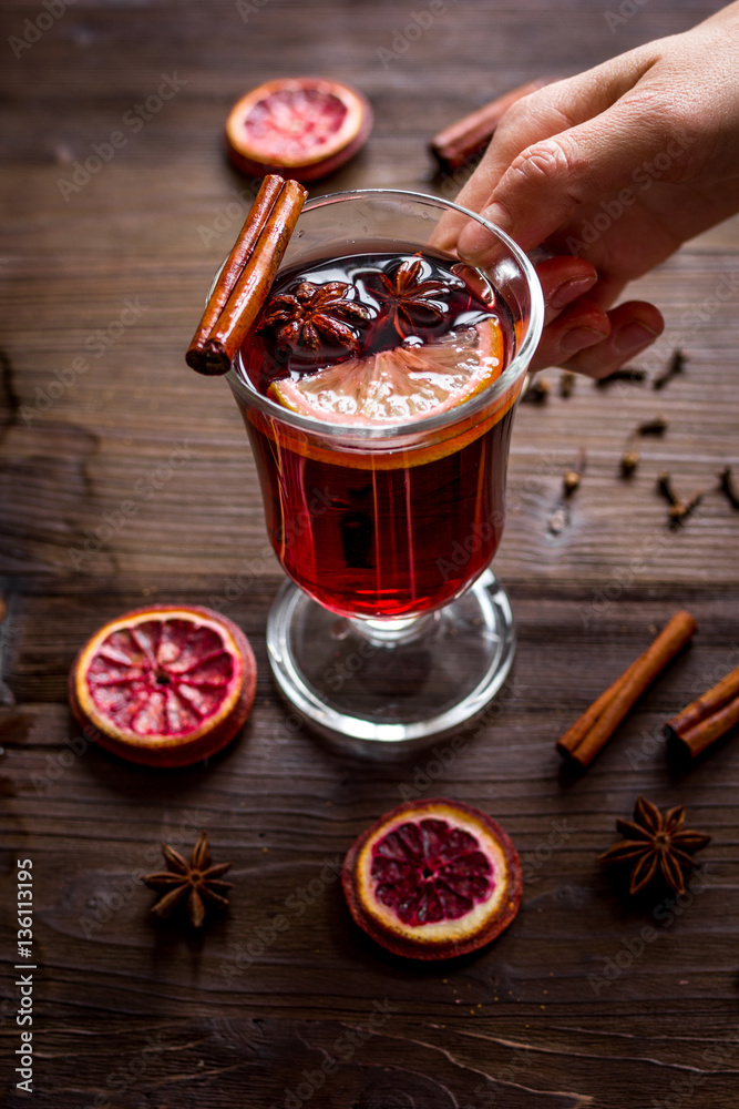 mulled wine with spices in cup on wooden background