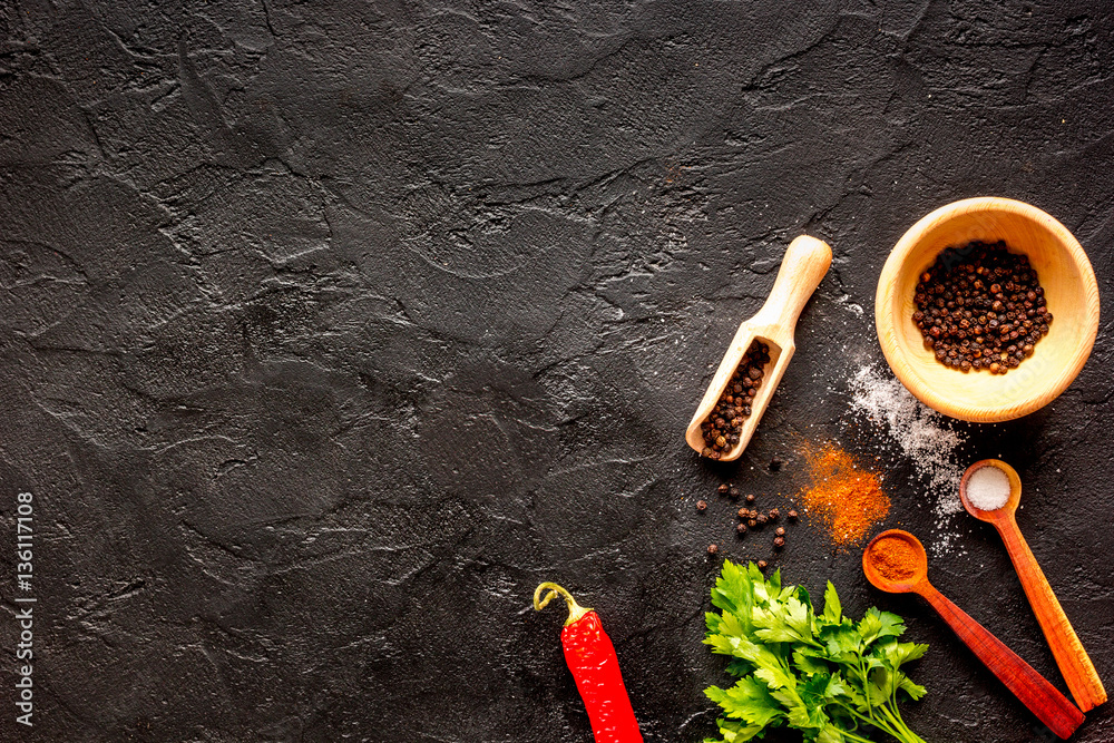 spices in wooden spoon on dark background top view