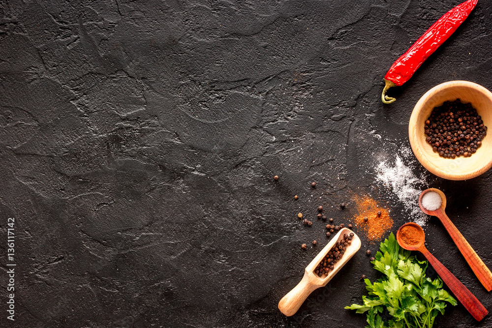 spices in wooden spoon on dark background top view