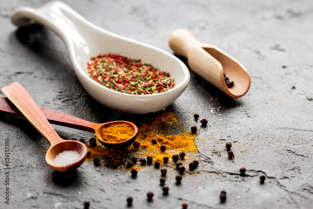 spices in wooden spoon on dark background