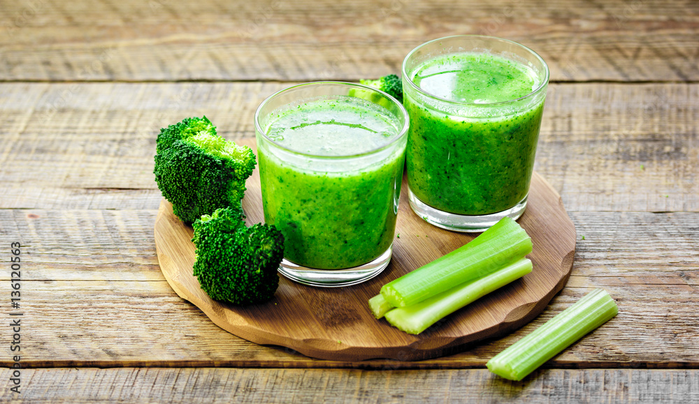 Green vegetable smoothie in glass at wooden background