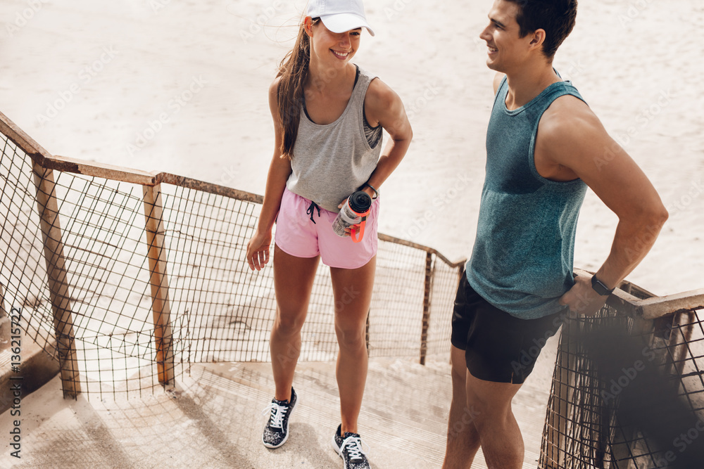 Fitness couple resting and talking at the beach