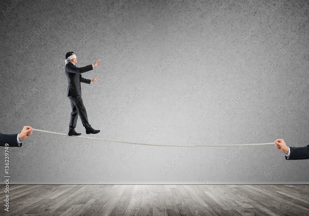 Business concept of risk support and assistance with man balancing on rope