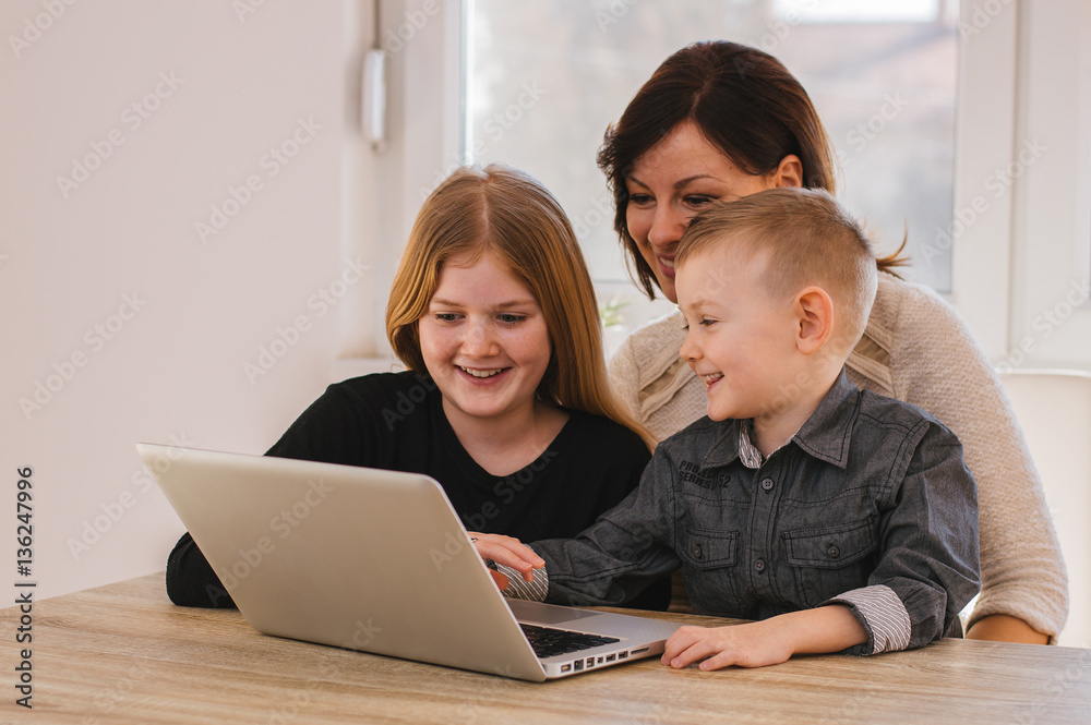 Mother with kids playing on laptop computer