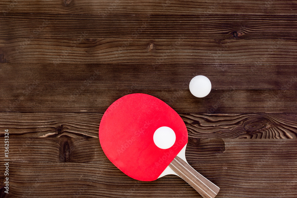 Red racket for ping pong ball wooden background top view