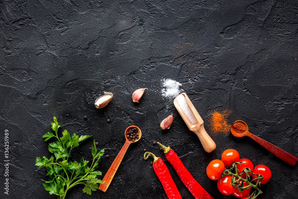 spices in wooden spoon on dark background top view