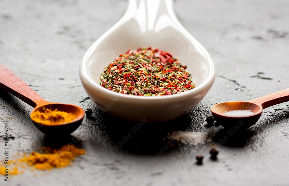 spices in wooden spoon on dark background