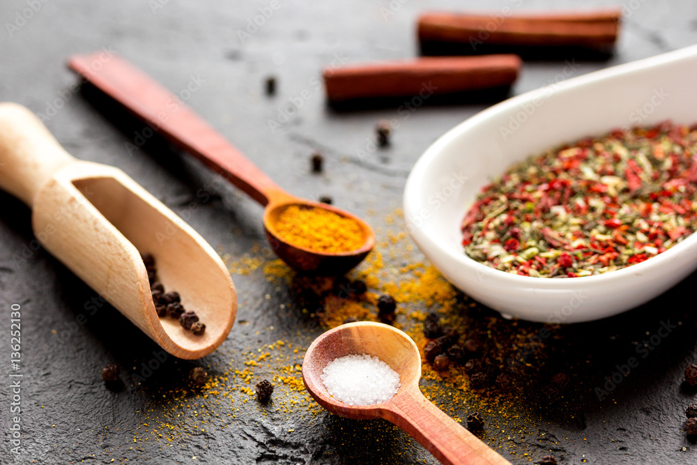 spices in wooden spoon on dark background