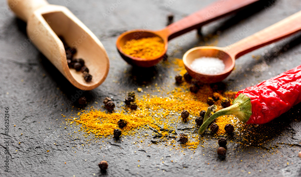 spices in wooden spoon on dark background