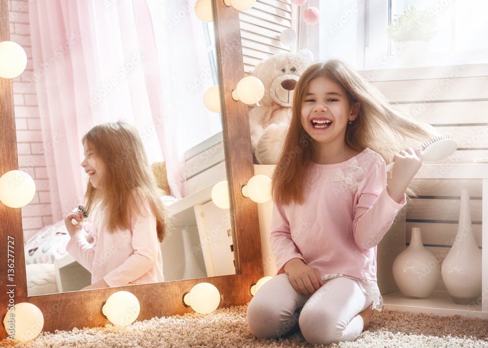 child is combing near mirror