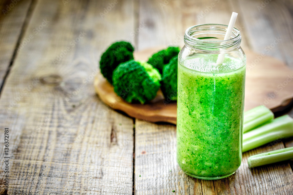 Green vegetable smoothie in glass at wooden background