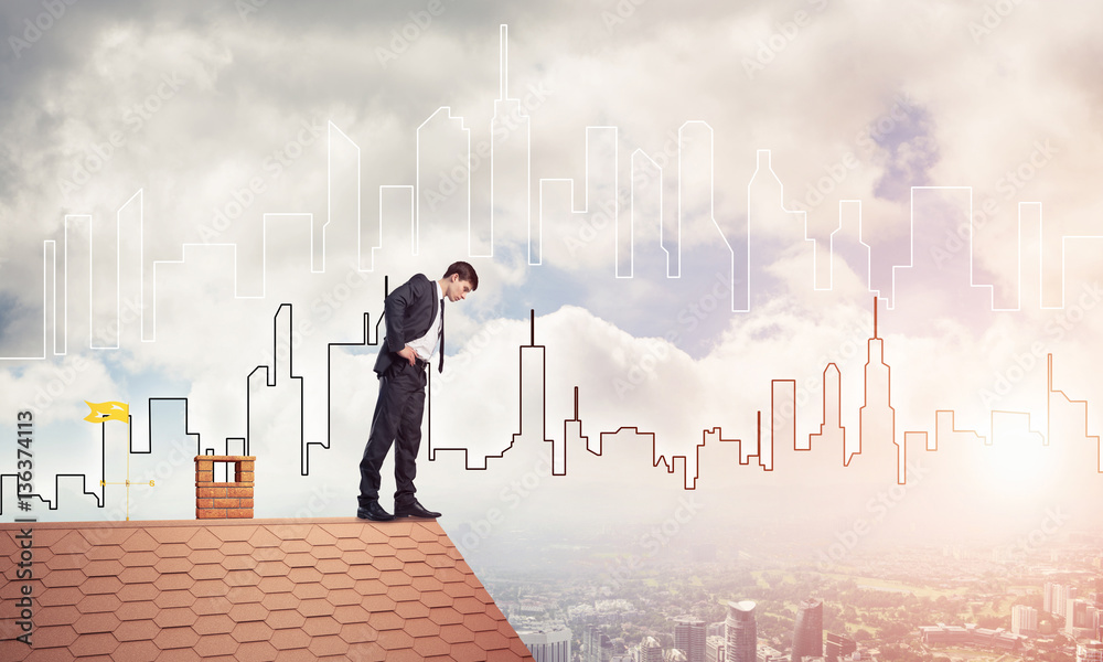 Businessman looking down from roof and modern cityscape at backg