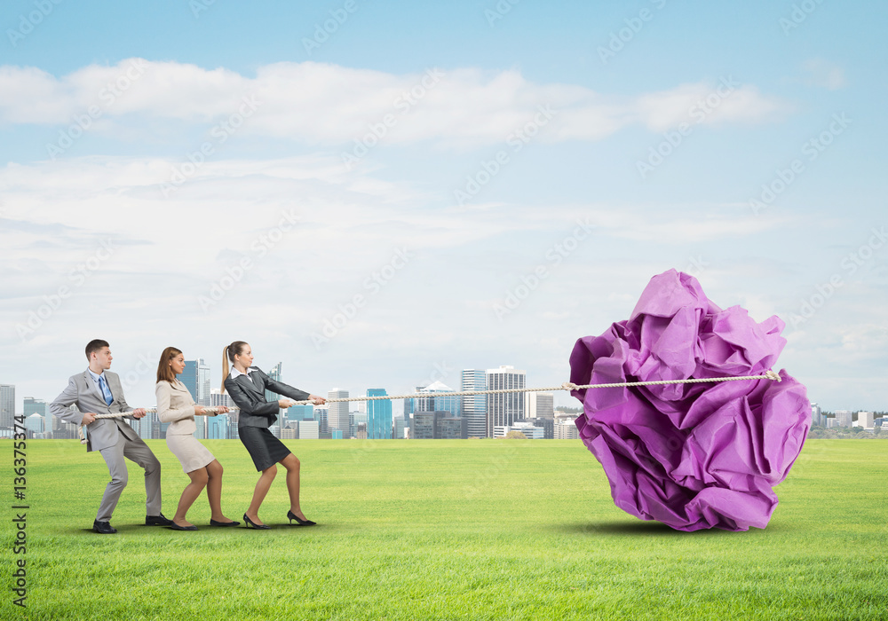 Young business people outdoors and huge paper ball as symbol of creativity