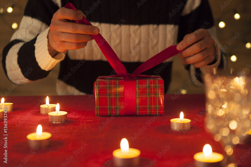 The man is opening the ribbon of the gift box