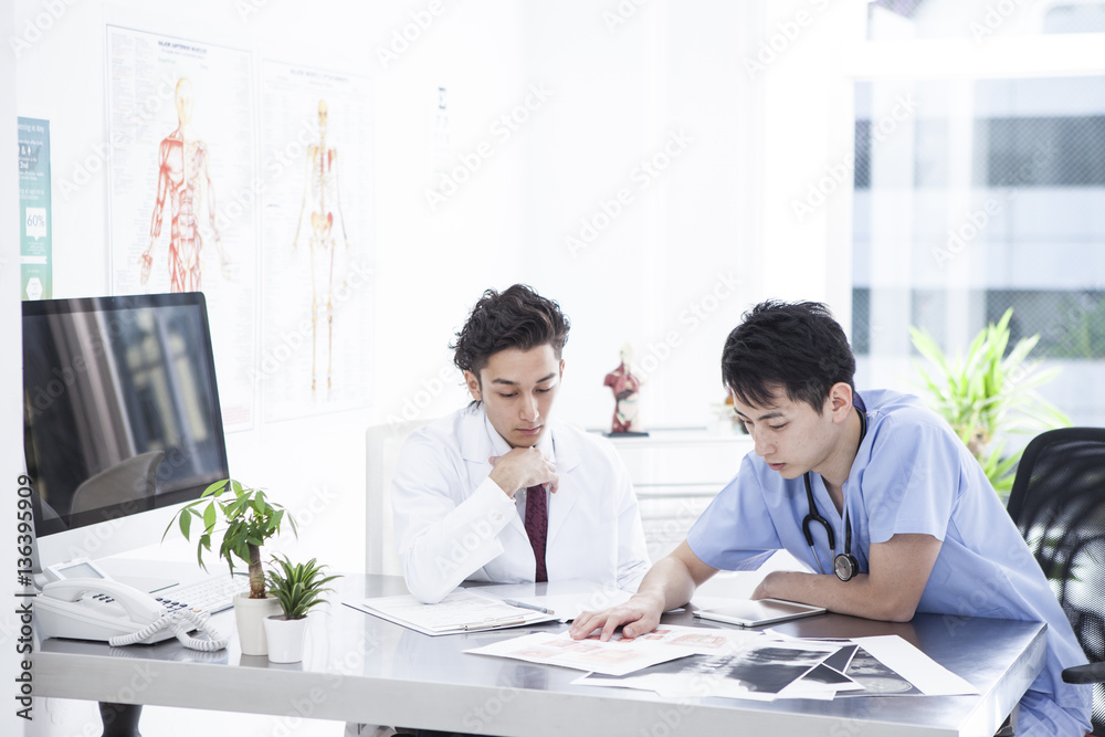 Two doctors are seriously talking in the examination room