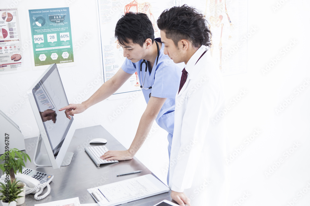 Two doctors are talking while watching a personal computer