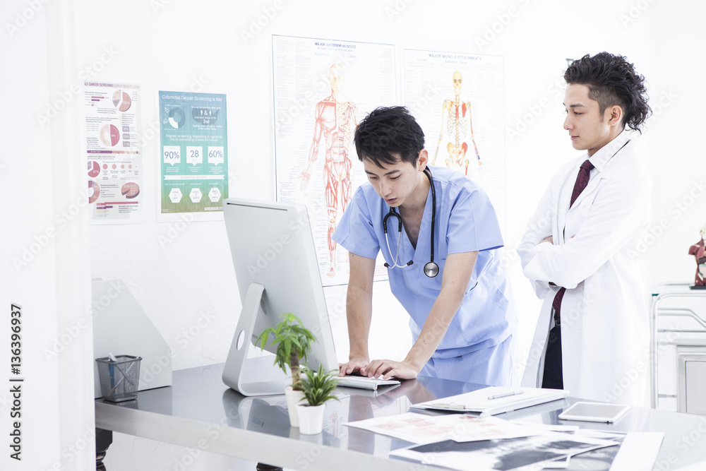 Two doctors are talking while watching a personal computer