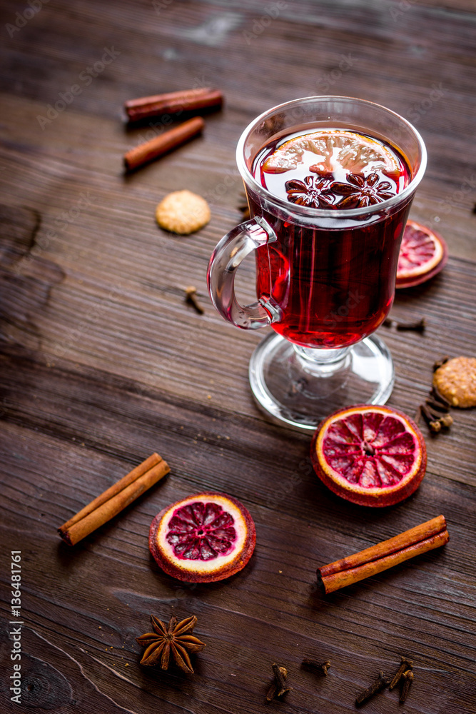 mulled wine with spices in cup on wooden background