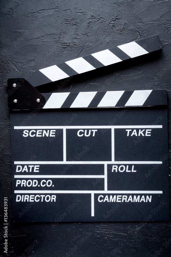 Screenwriter desktop with movie clapper board dark background top view