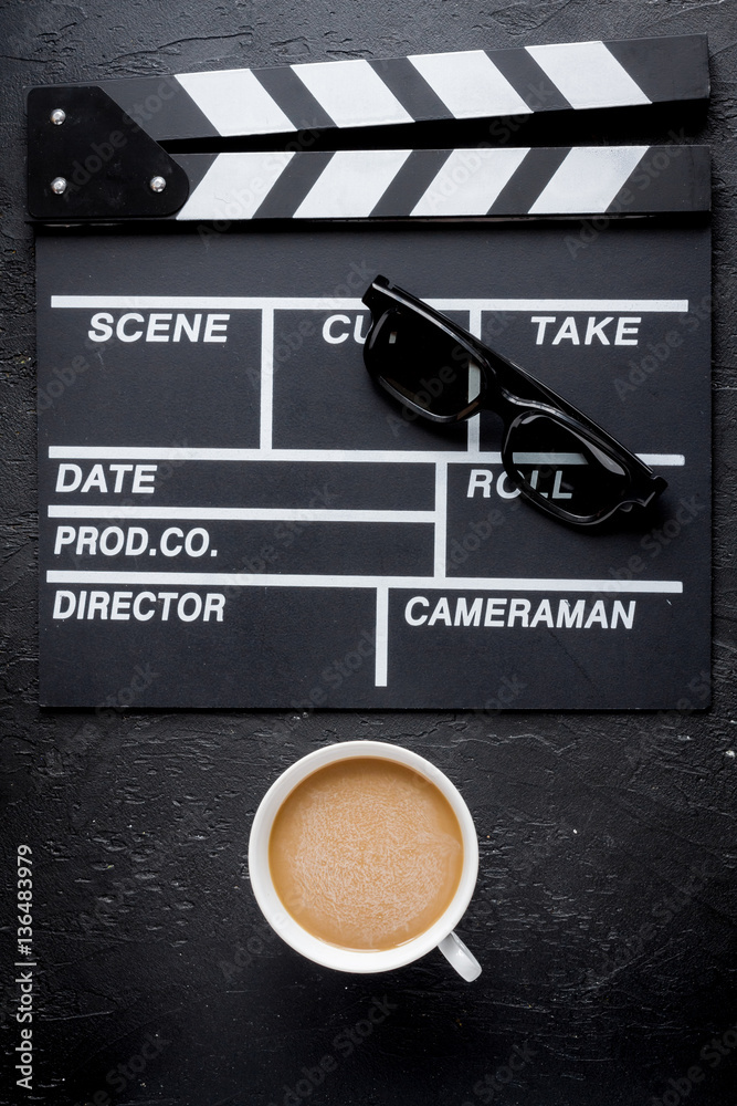 Screenwriter desktop with movie clapper board dark background top view