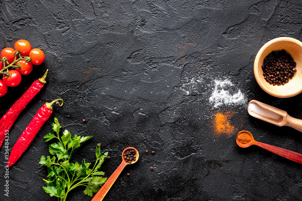 spices in wooden spoon on dark background top view