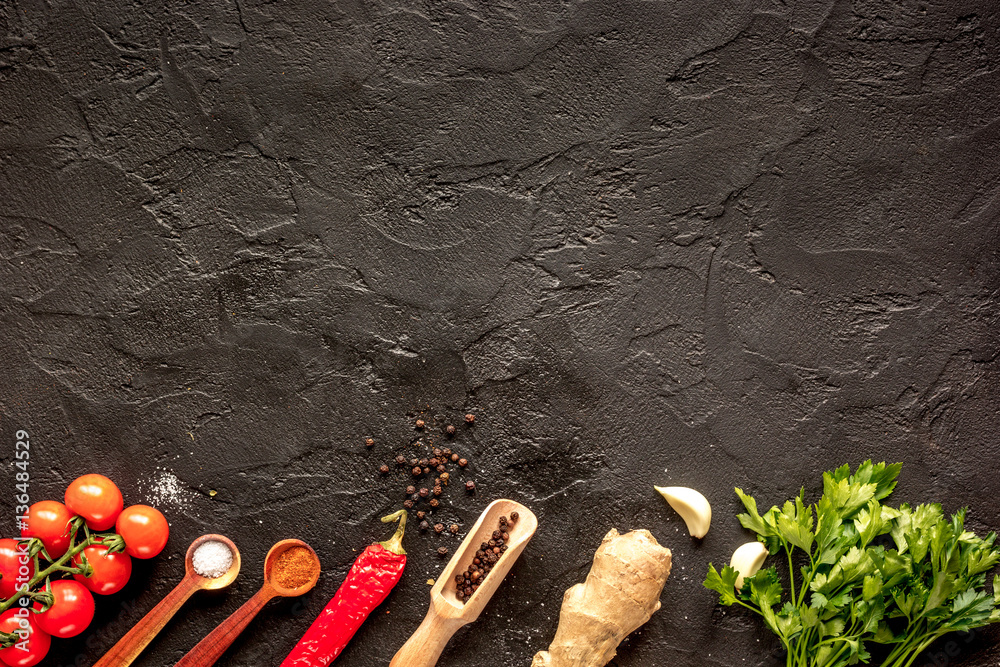 spices in wooden spoon on dark background top view