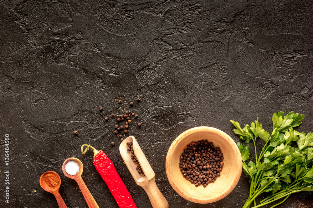 spices in wooden spoon on dark background top view