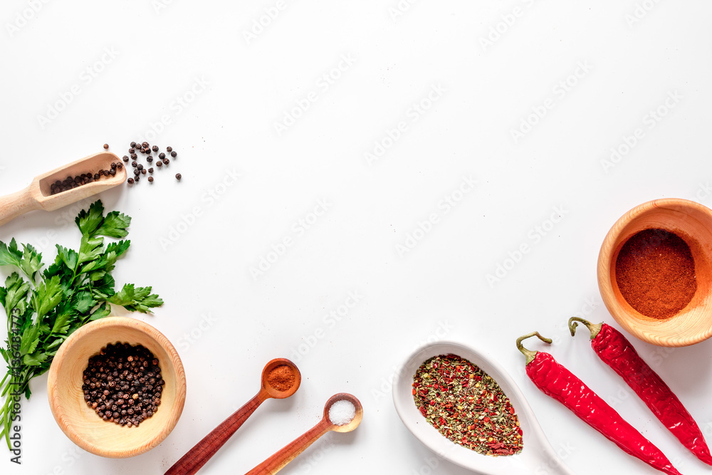 spices in wooden spoon on white background top view