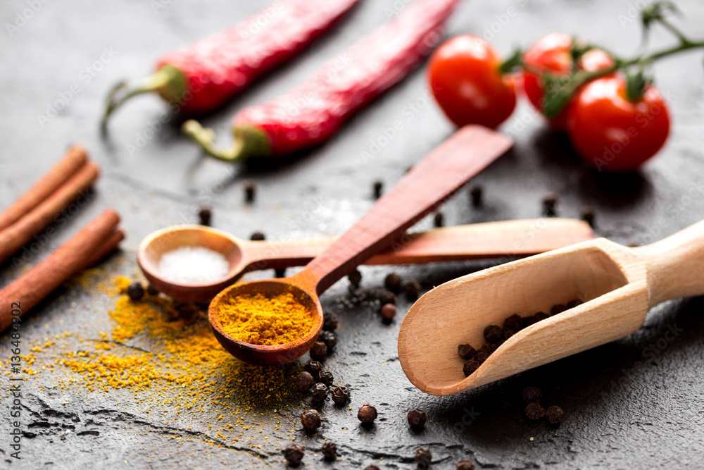 spices in wooden spoon on dark background