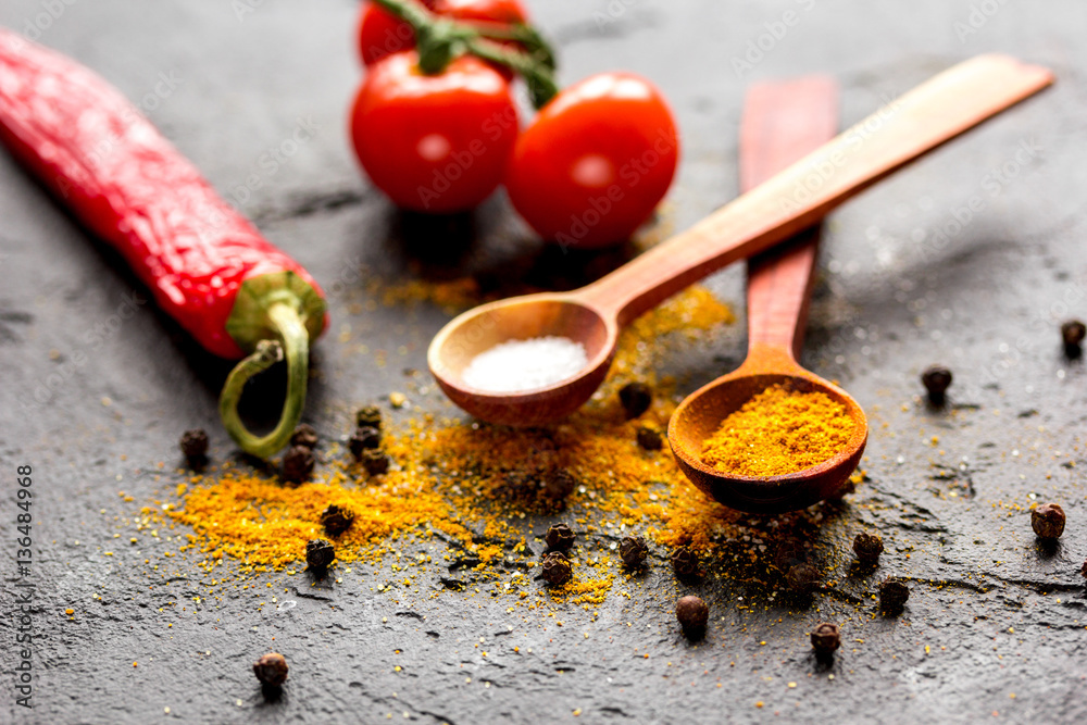 spices in wooden spoon on dark background