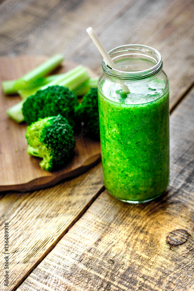 Green vegetable smoothie in glass at wooden background