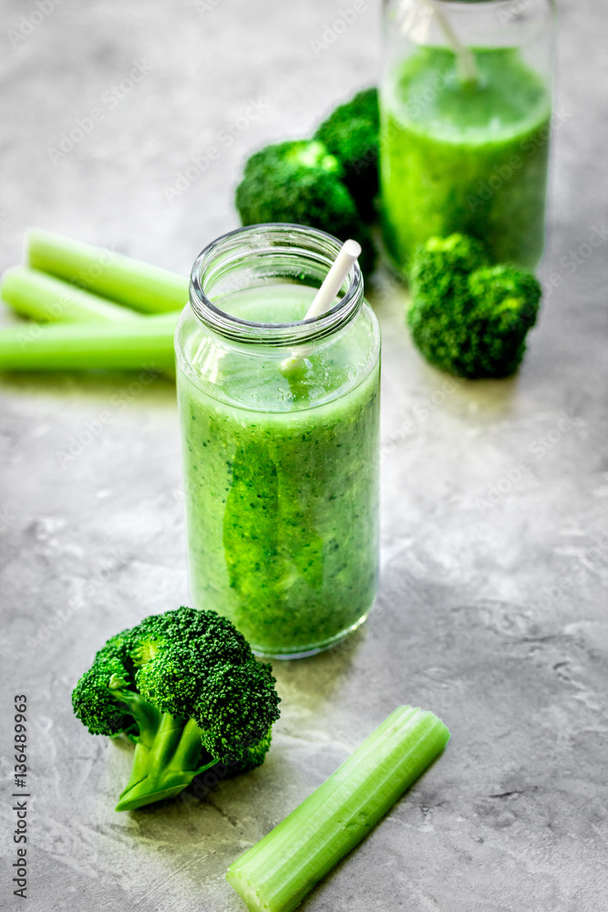 Green vegetable smoothie in glass at gray background