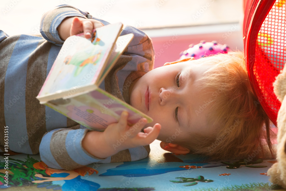 Little boy reading a book on the floor