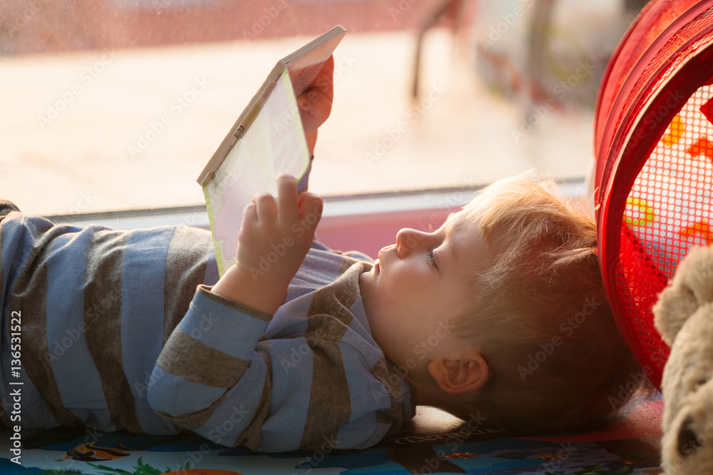 Little boy reading a book on the floor