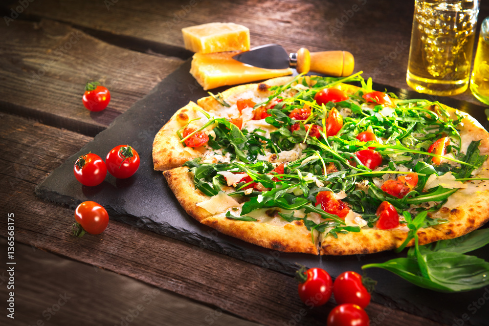 Pizza Caprese with arugula, cheese, yoghurt and cherry tomatoes closeup