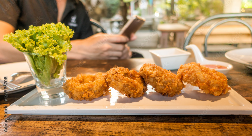 Thai fried fish patty with man using smart phone