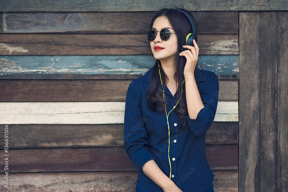 happy asian woman listening to music on her headphone and holdin